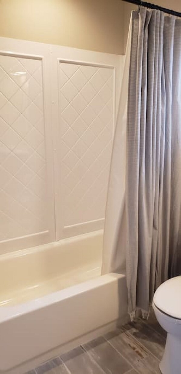 A bathroom with a white bathtub, a toilet, and a shower curtain. - Change in Altitudes \ 3 bed, 2.5 bath lux house on 20 acres near Yellowstone (Emigrant)