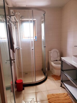 A bathroom with a glass-enclosed shower, a toilet, and a sink. - Lux Suites Stunning Homes Kilimani (Nairobi)