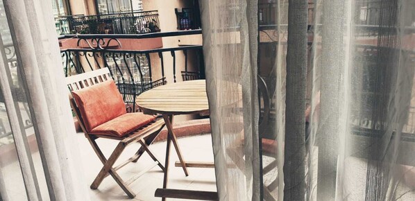A balcony with a wooden table and a cushioned chair, a wrought iron railing, and a view of the cityscape. - Lux Suites Stunning Homes Kilimani (Nairobi)