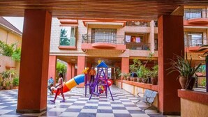 A covered outdoor area with a playground, potted plants, and a checkered floor. - Lux Suites Stunning Homes Kilimani (Nairobi)