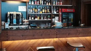 A bar area with shelves of liquor bottles, a coffee machine, and a Coca-Cola refrigerator. - Sestriere apartment in residence with veranda (Sestriere)