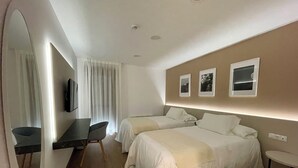 A hotel room with two beds, a desk, a chair, a mirror, and a small table. - La Hospederia - El Provencio (El Provencio)
