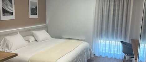 A modern bedroom with a bed, a desk, and a chair.