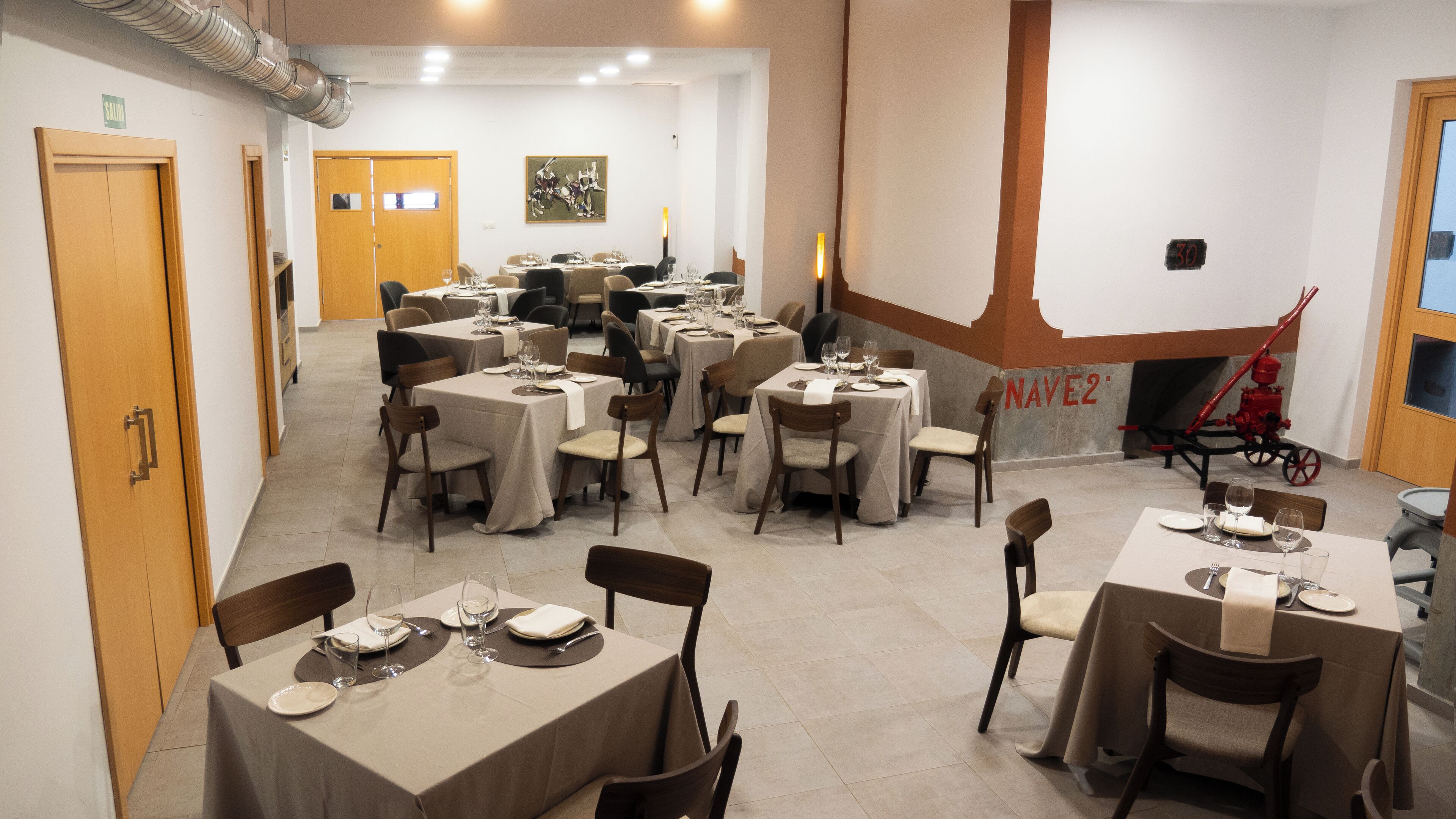 A dining area with multiple tables set for meals, chairs, and a wall-mounted clock.