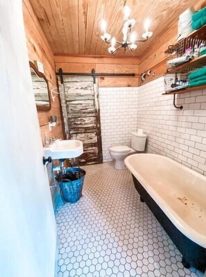Bathroom features a white sink, toilet, and black bathtub.