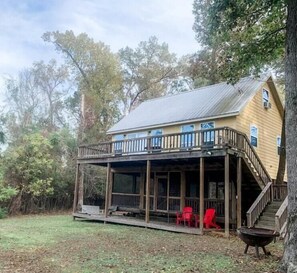 Enjoy a peaceful retreat with a covered porch and balcony overlooking the surrounding trees and lawn.