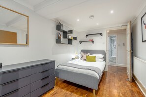Une chambre moderne comprenant un lit, des tables de chevet, une commode et des étagères intégrées.