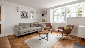 Ein Wohnzimmer mit einer Couch, zwei Sesseln, einem runden Couchtisch und einem großen Fenster mit Blick.