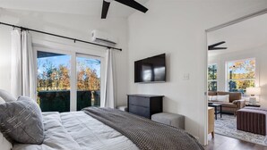 Un dormitori amb un llit gran, una televisió penjada a la paret i vista a l'exterior.