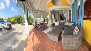 A covered outdoor patio with a pool, seating area, and a view of the pool.
