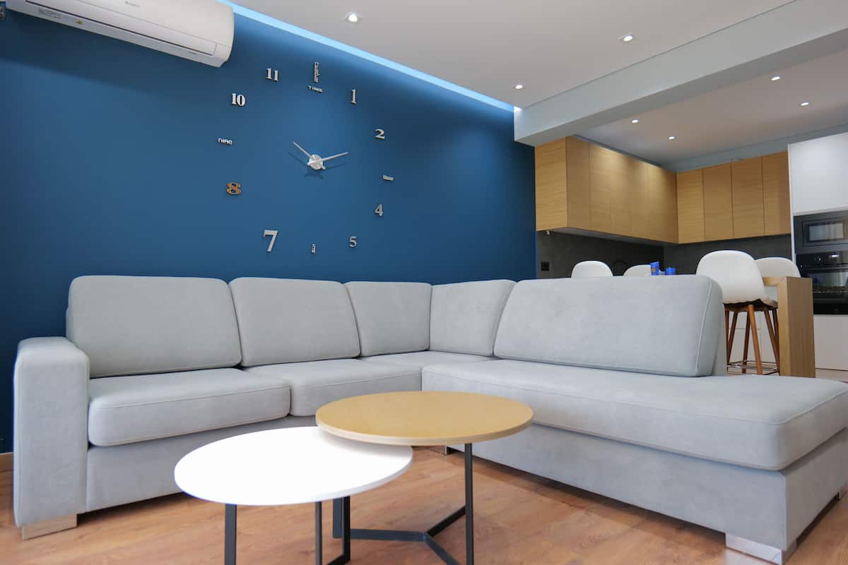 A modern living room with a sectional sofa, a small round table, and a wall clock.