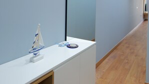 Un baño moderno con un tocador blanco, un espejo grande y suelo de madera.