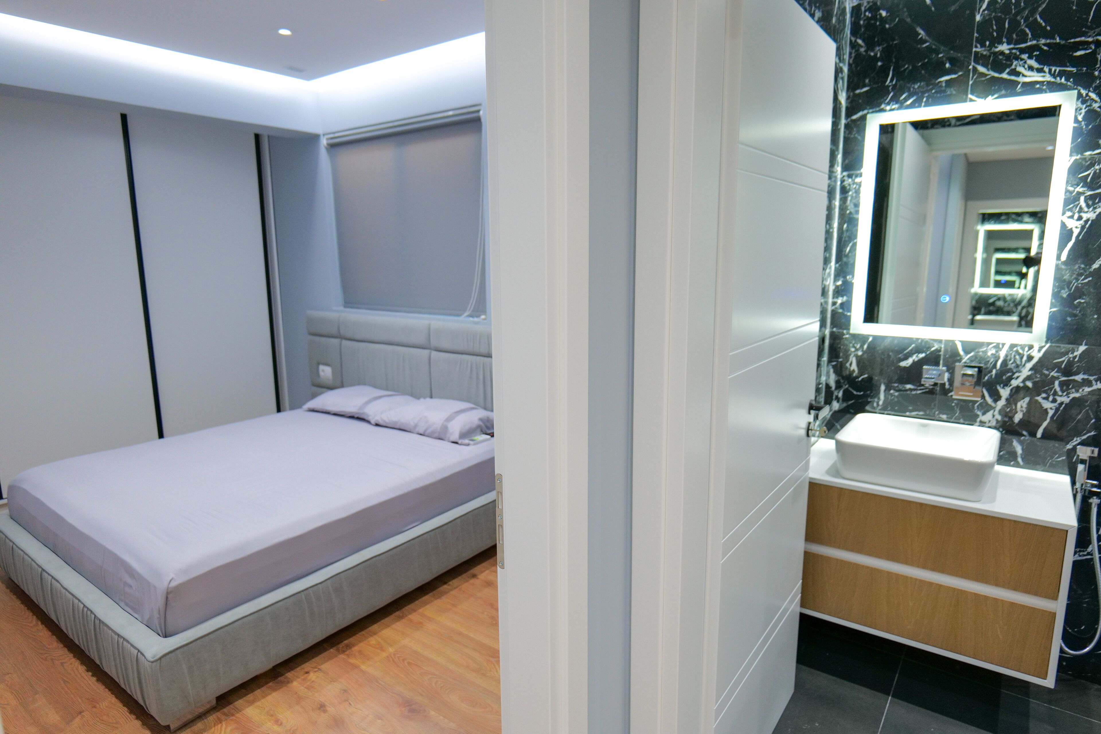 A modern bedroom with a bed, a bedside table, and a built-in headboard.