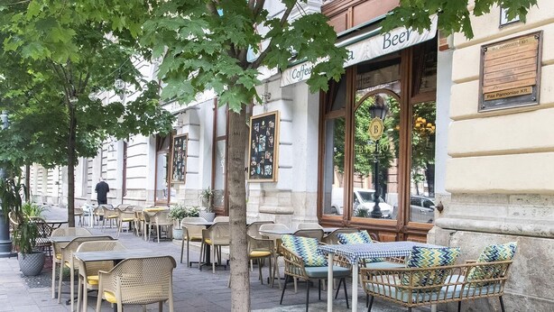 An outdoor café with wicker chairs and tables, a sign for 'Beer Coffee', and a building with a plaque. - Joyful Place   Stay in City Center (Budapest)