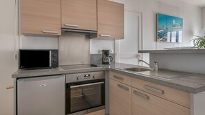 A modern kitchen with wooden cabinets, a built-in oven, a microwave, and a sink.