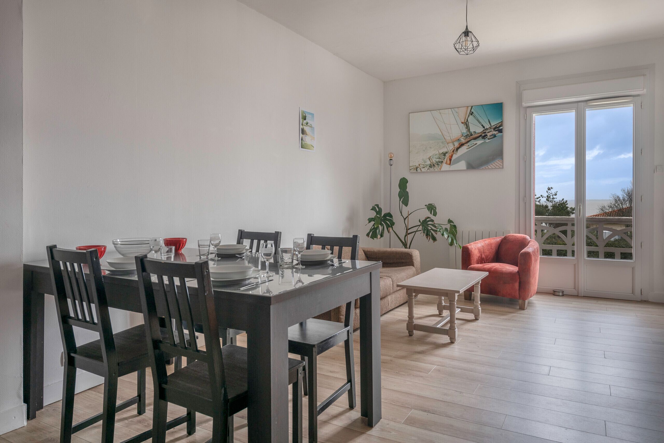 Un comedor con una mesa de madera dispuesta para cuatro personas, un sofá y un sillón rojo.