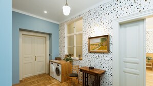 A compact kitchen with a washing machine, a wooden table, and a window with a view of a landscape.