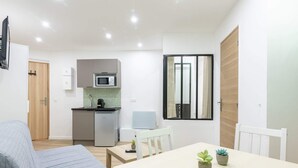 A compact living space with a kitchenette, a dining area, and a bed. - Buttes Chaumont 3 - One Bedroom Apartment, Sleeps 4 (Paris)