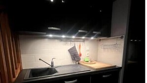 Uma cozinha moderna com armários pretos, pia de aço inoxidável e bancada de madeira.
