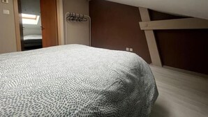 Quarto com cama, claraboia, guarda-roupa e cabideiro.