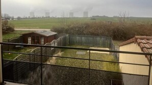 Vista de varanda com paisagem rural, um pequeno edifício e uma cerca.
