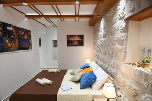 Une pièce chaleureuse avec un lit, un mur en pierre et des œuvres d’art accrochées aux murs.