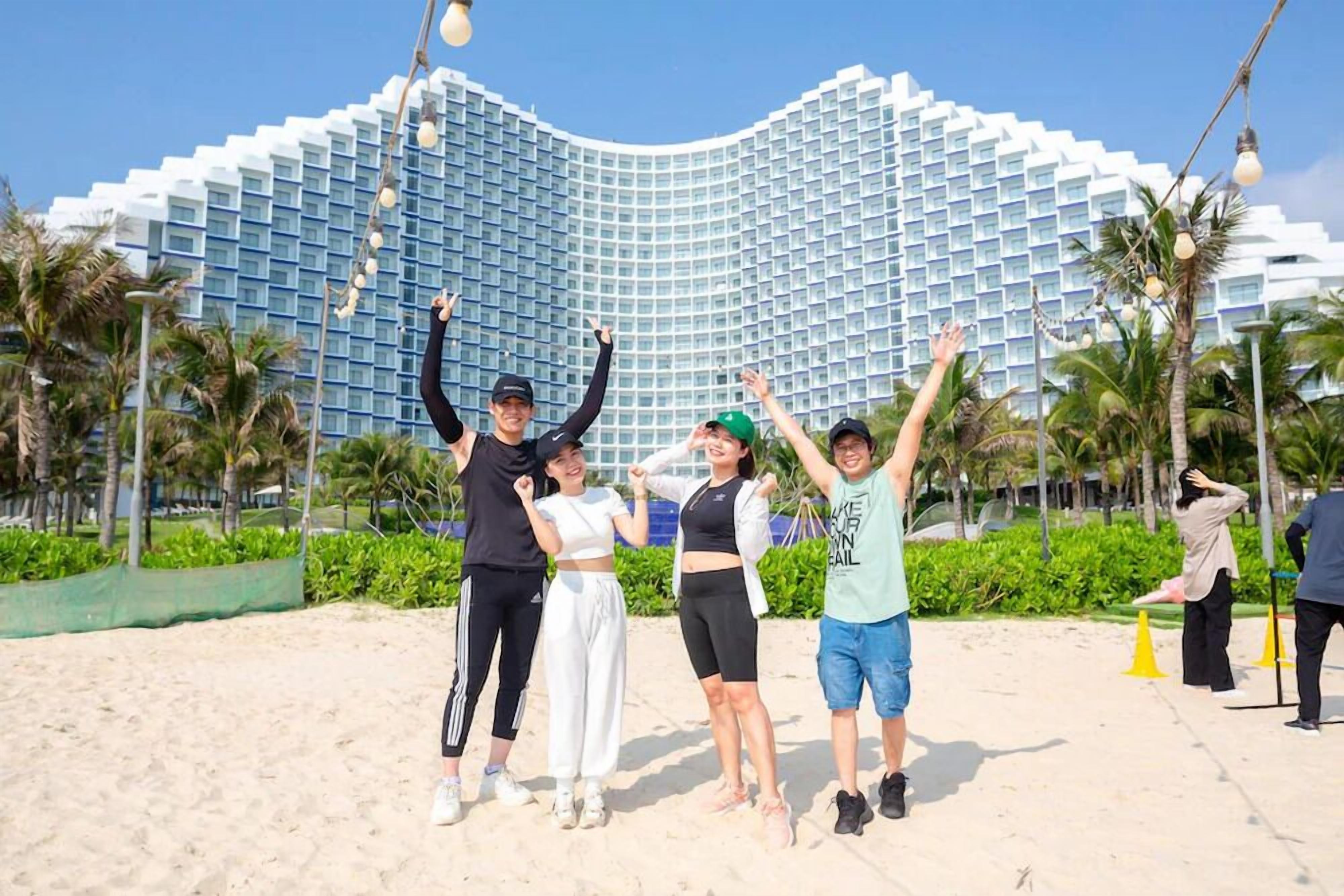 A group of people posing in front of a modern hotel with a distinctive curved facade.
