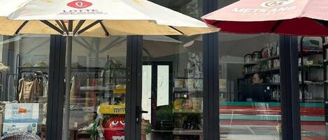 Un escaparate con un letrero que dice 'Taka Signature' y dos sombrillas en primer plano.