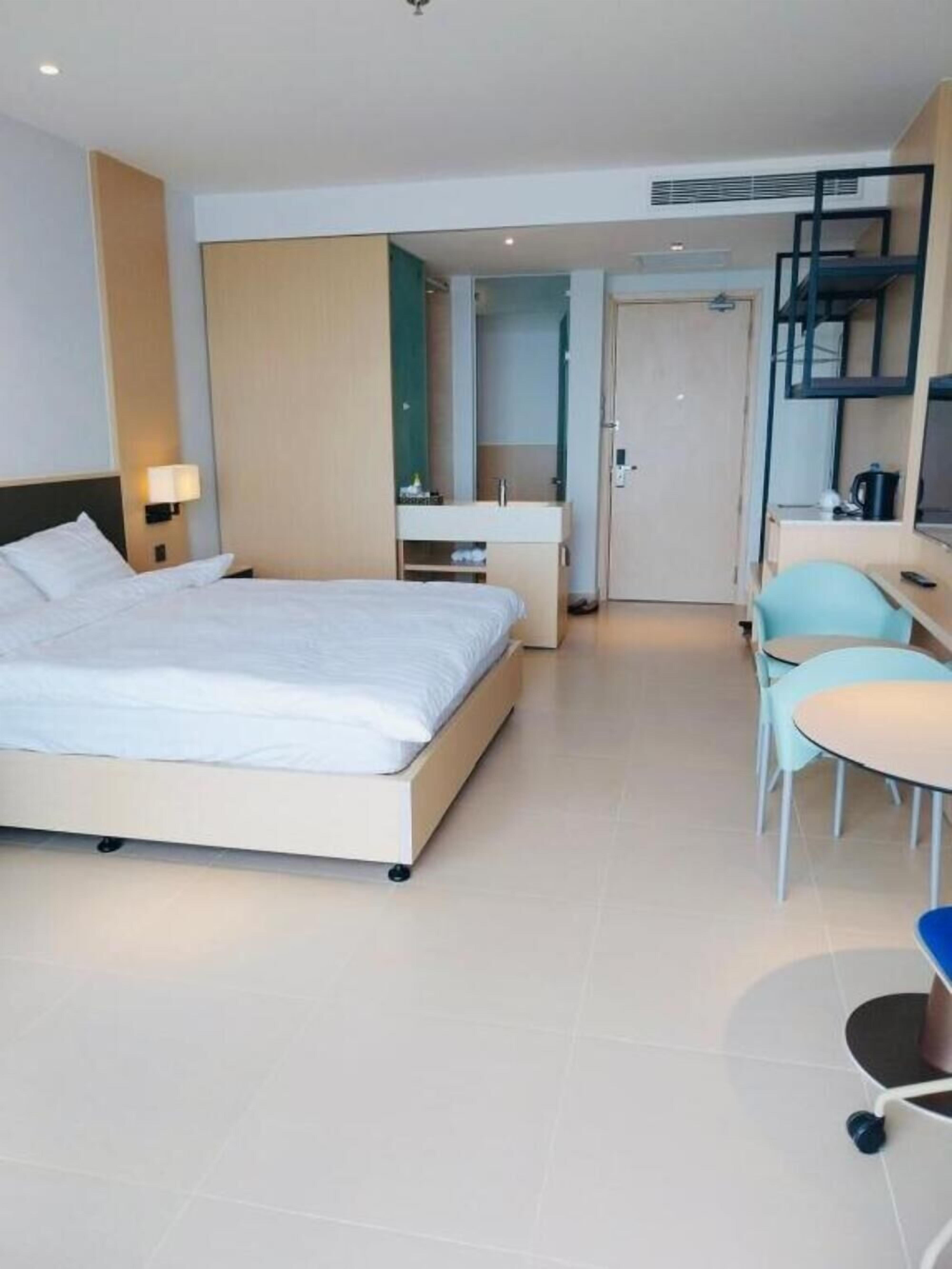 Et moderne hotelværelse med seng, skrivebord, stol og et lille tekøkken.