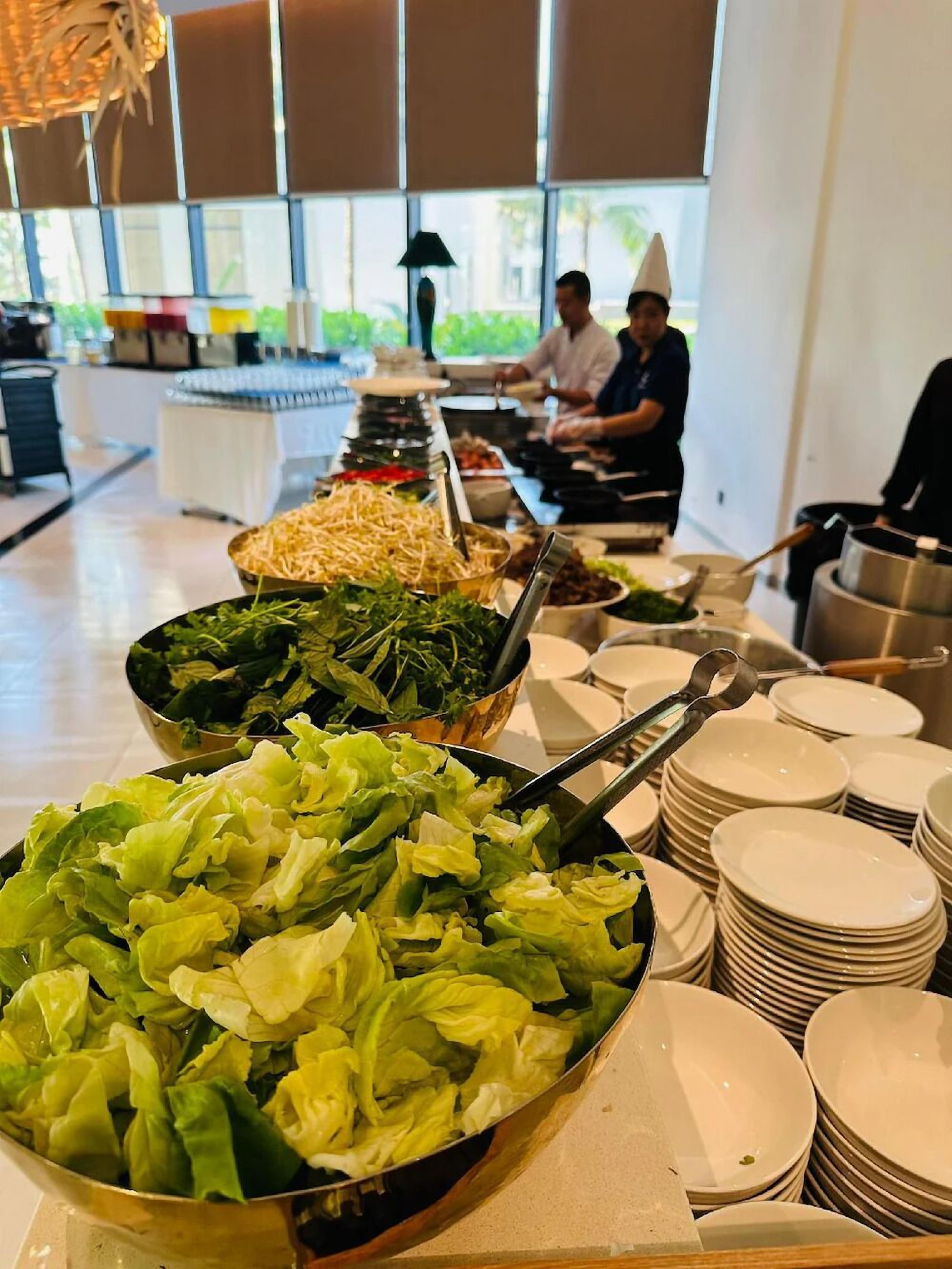 Un buffet proposant une variété de plats et où les assiettes sont empilées.