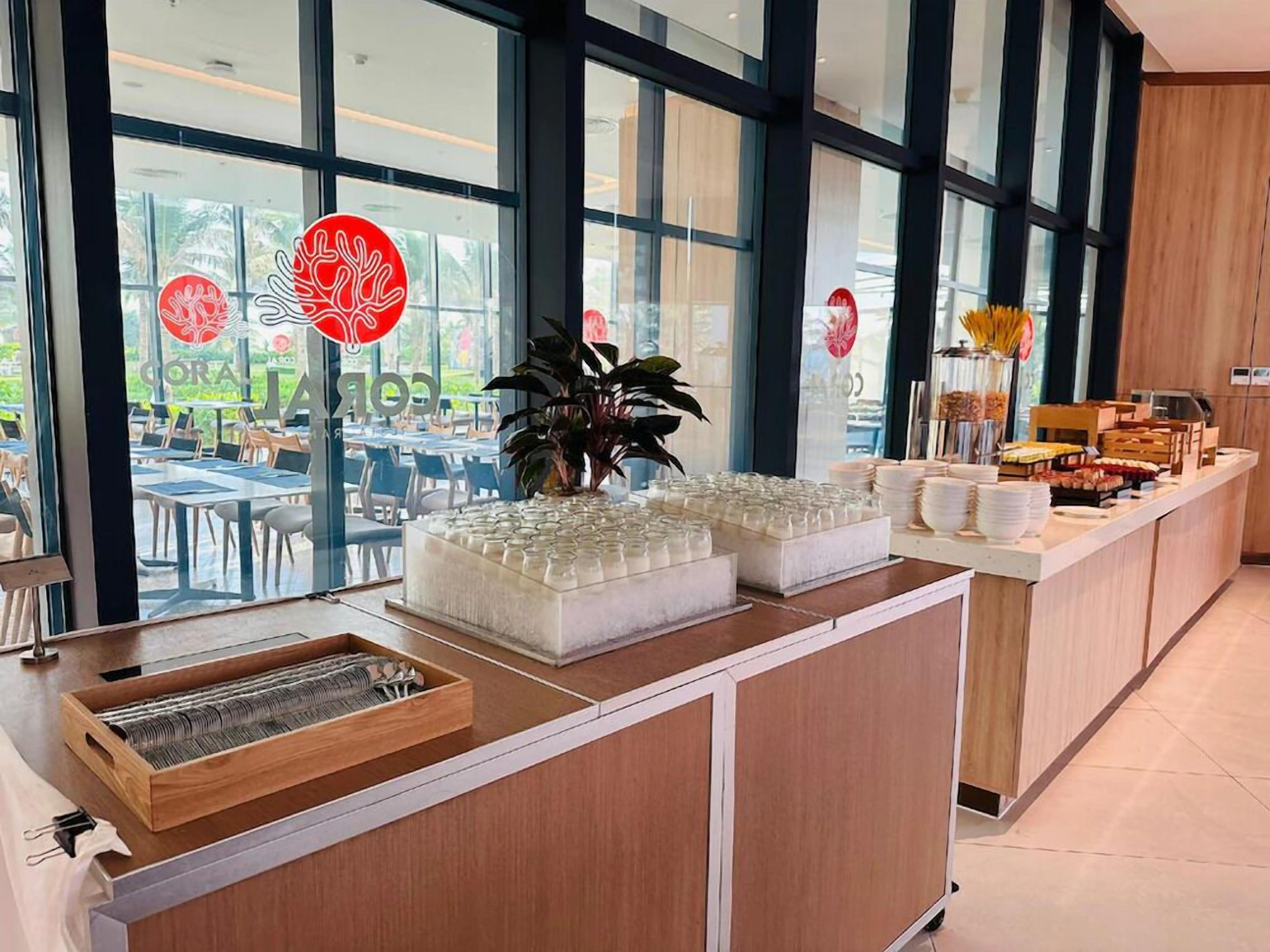 A buffet area with a glassware display, a plant, and a variety of food items.