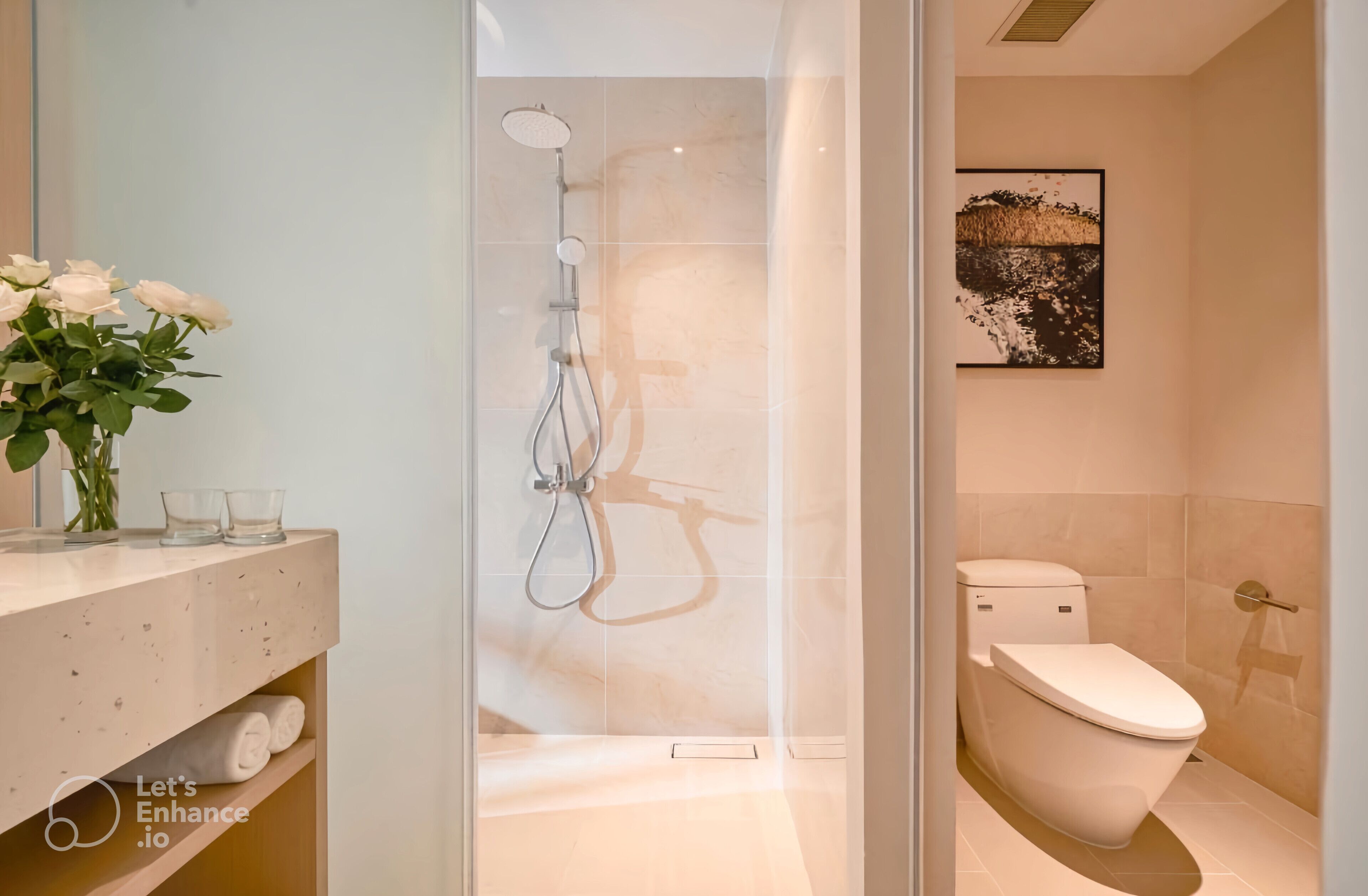 Une salle de bain moderne avec une douche en verre, des toilettes et un lavabo agrémenté d’un vase de fleurs blanches.