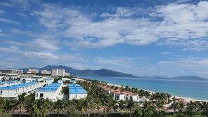 Un complexe hôtelier comprenant plusieurs bâtiments, une plage et des montagnes en arrière-plan.