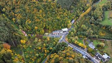 Vista aérea de una zona boscosa con una carretera, edificios y un estacionamiento.