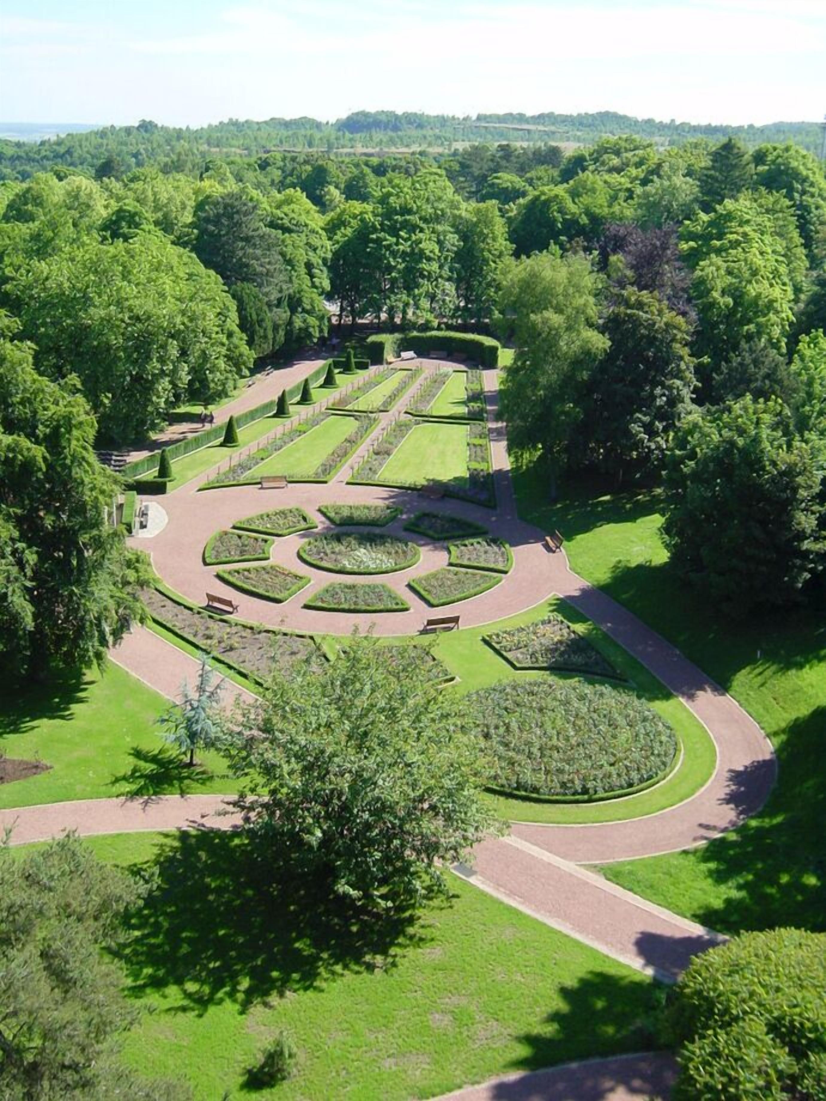 An aerial view of a formal garden with geometric pathways and neatly trimmed hedges.