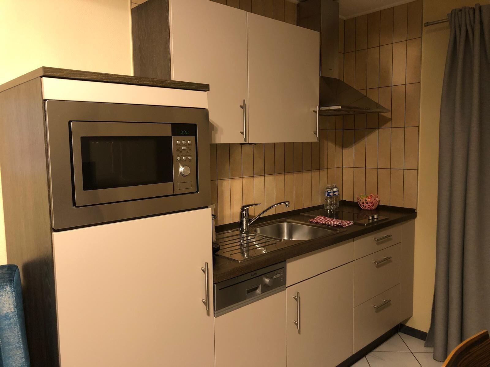 A compact kitchen with a built-in microwave, a stainless steel sink, and a dishwasher.