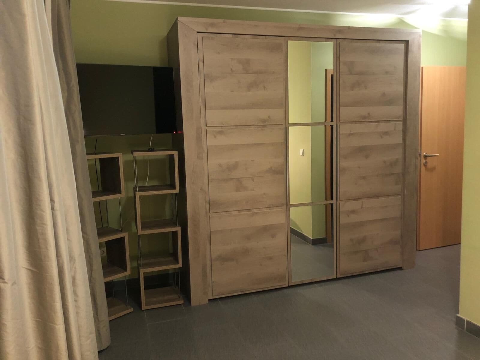 Ein Zimmer mit Kleiderschrank, Spiegel und Regalelement.