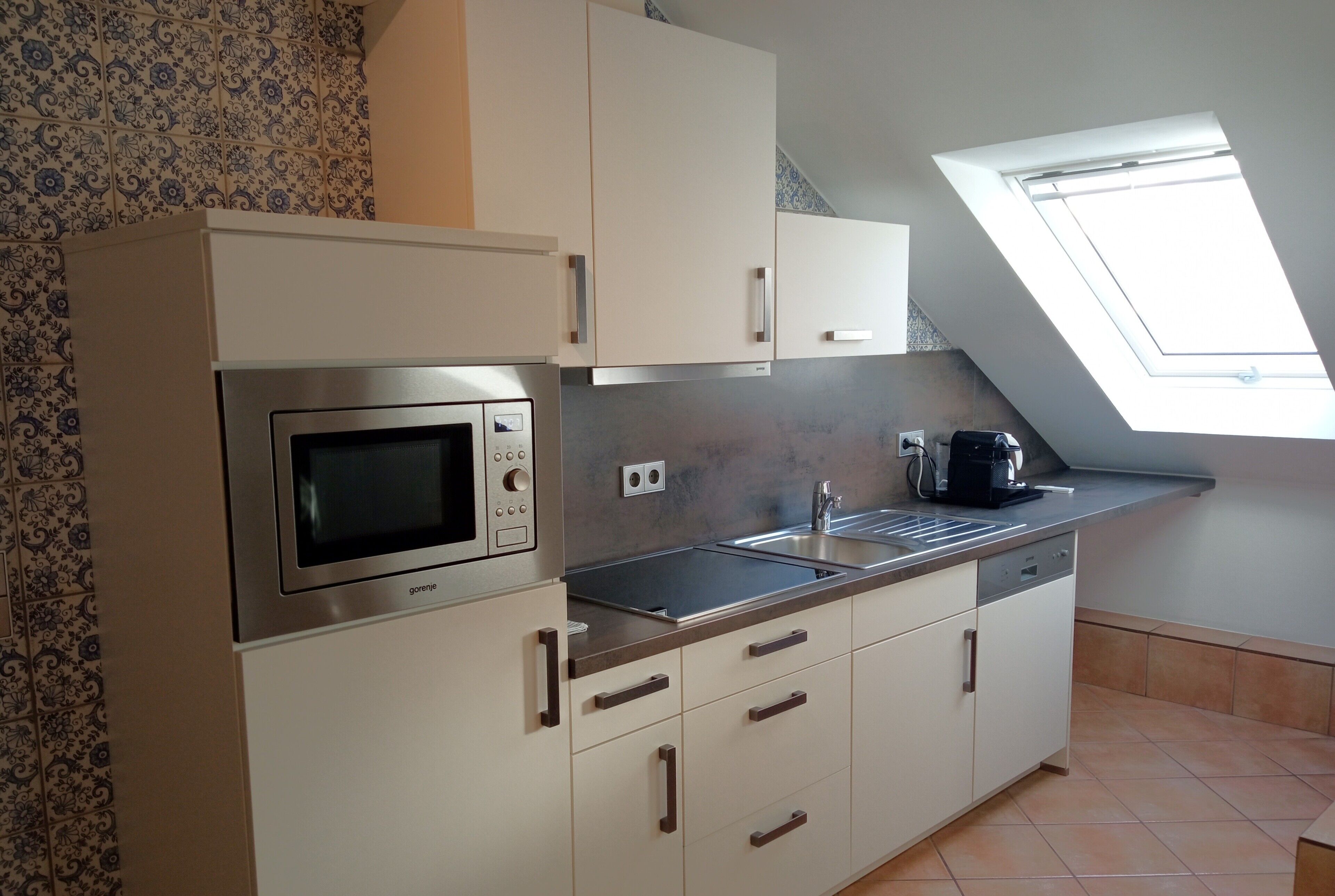 A modern kitchen with a built-in microwave, stainless steel sink, and white cabinets.