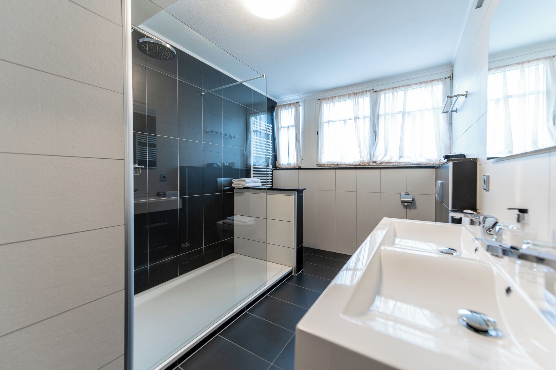 A modern bathroom with a glass shower enclosure, a white sink, and a mirror.