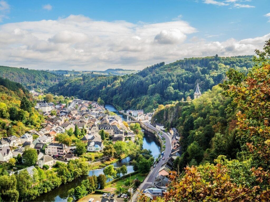 A town with a river, surrounded by hills and greenery.