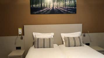 A double bed with striped pillows, a headboard, and a nightstand with a lamp.