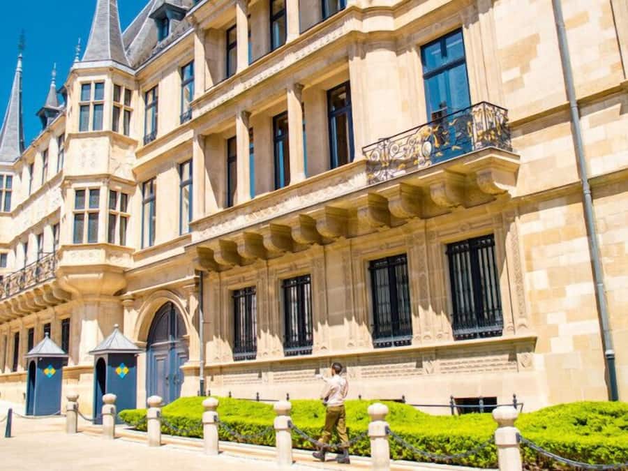 Un edificio histórico con arquitectura ornamentada, ventanas amplias y un jardín bien cuidado.