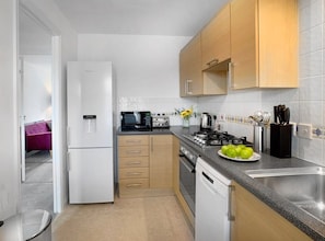 A compact kitchen with a refrigerator, stove, and sink.