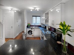 A modern kitchen with a built-in washer and dryer, a large window, and a black granite countertop. - 2 BedTerrace House, Garden, Parking (Knaphill)
