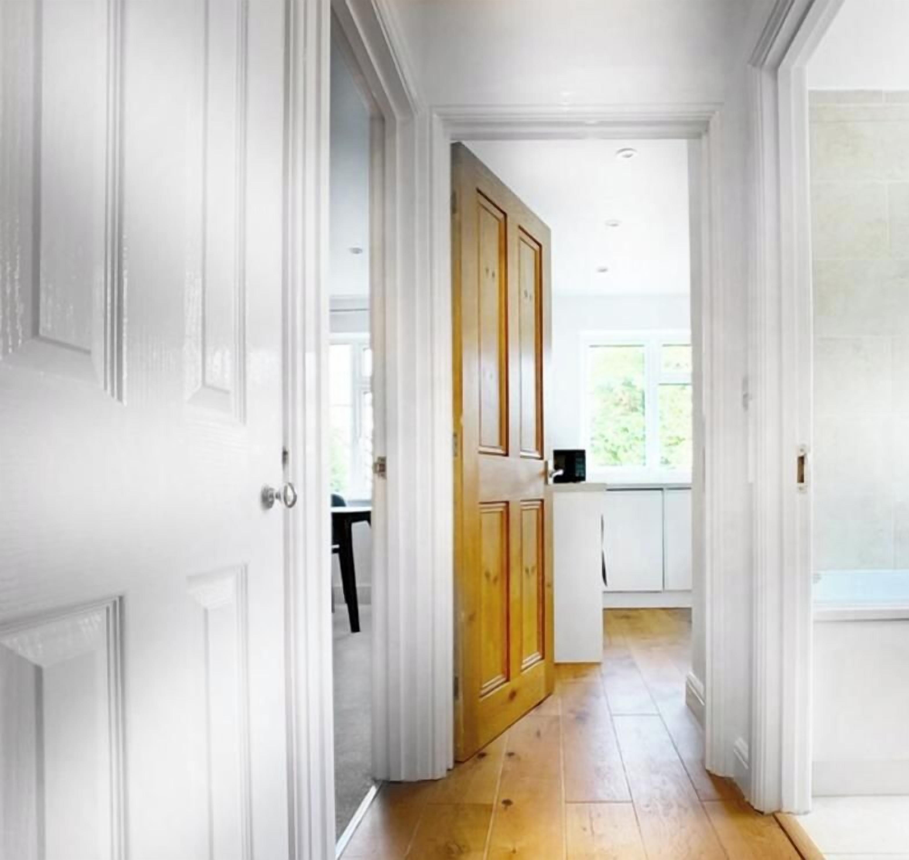 Un pasillo con puertas blancas que dan a una zona de cocina.
