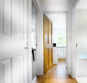 A hallway with white doors leading to a kitchen area. - Ascot - Cottage, Garden, Parking (Sunningdale)
