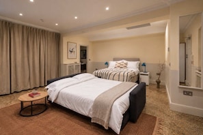 A hotel room with a large bed, bedside tables, a small round table, and a mirror.