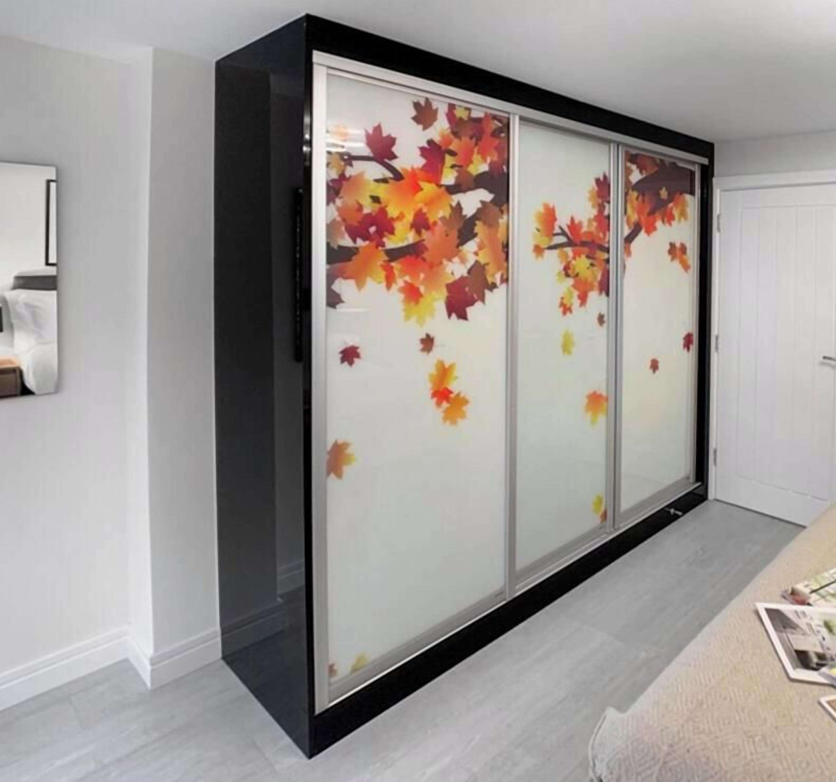 A room with a sliding door featuring autumn leaf decals, a white door, and a light-colored floor.