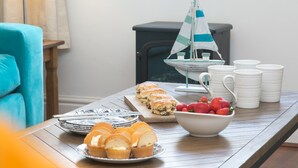 A dining table with pastries, a sailboat decoration, and white mugs. - Breeze Cottage  2 bed Beach property - Pass the Keys (Rhosneigr)