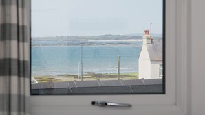 A window view of a coastal area with a white building and a clear sky. - Breeze Cottage  2 bed Beach property - Pass the Keys (Rhosneigr)
